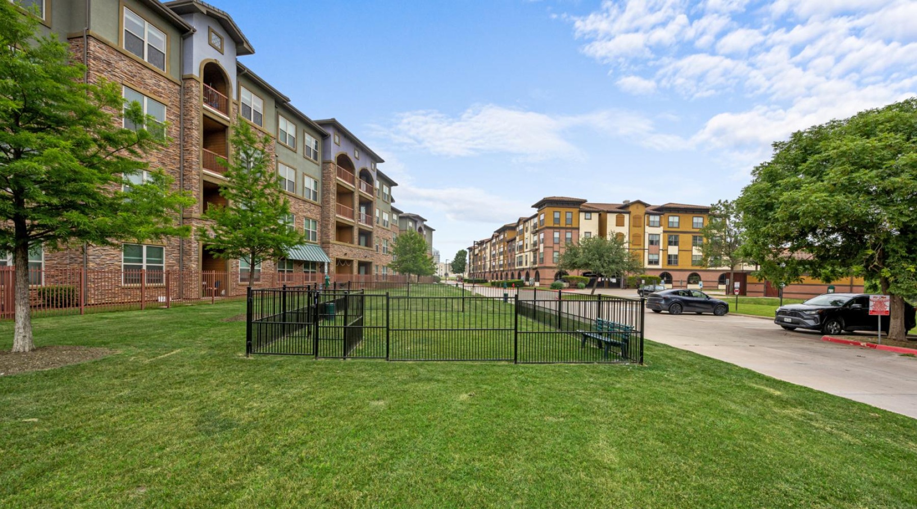 a green lawn in front of a building with a fenced in area