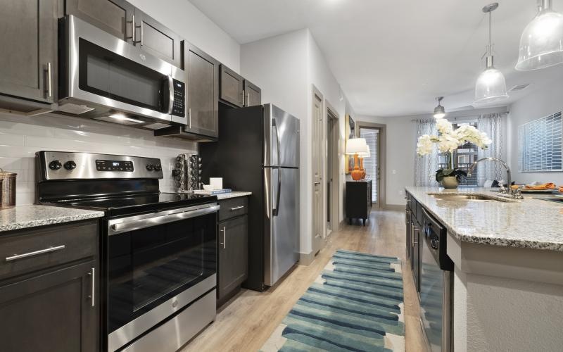 a kitchen with dark cabinets and stainless steel appliances